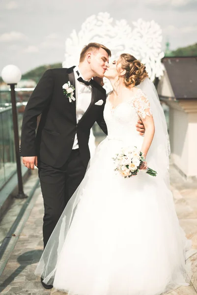 Krásný šťastný svatební pár, nevěsta s dlouhými bílými šaty pózuje v krásném městě — Stock fotografie