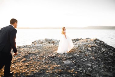 Güzel bir sahilde poz veren genç bir çiftin mutlu ve romantik sahnesi.