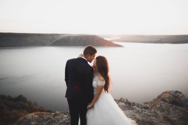 Düğün çifti, damat, Gelin günbatımı üzerinde denize yakın poz