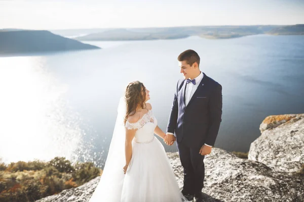 Şık, şık, mutlu bir düğün çifti, gelin, deniz ve gökyüzünün arka planında muhteşem bir damat.