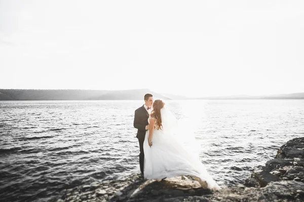 En lykkelig og romantisk scene der et ungt ektepar poserer på en vakker strand. – stockfoto