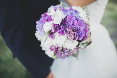 Gelin çiçekli büyük ve güzel bir düğün buketi tutuyor.