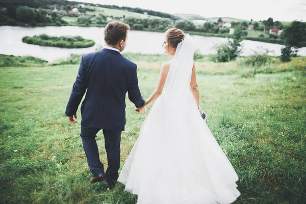 Нещодавно одружена пара бігає і стрибає в парку, тримаючись за руки — стокове фото