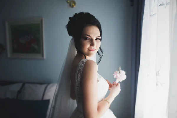 Preciosa novia en bata posando y preparándose para la ceremonia de boda cara en una habitación — Foto de Stock