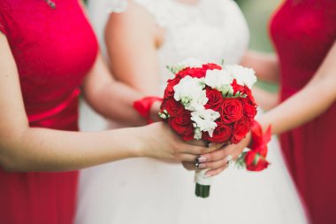 Gelin çiçekli büyük ve güzel bir düğün buketi tutuyor.