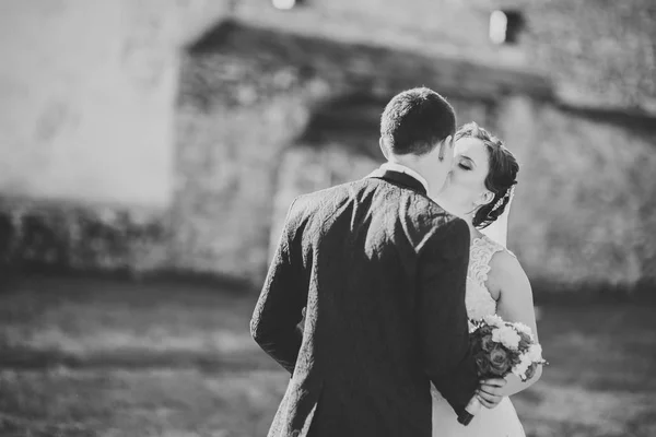 Beautiful romantic wedding couple of newlyweds hugging near old castle — Stock Photo, Image