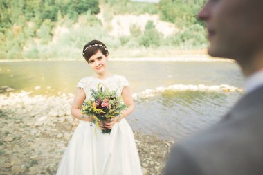 Zarif nazik şık damat ve gelin taşlarla Nehri yakınında. Evlilik çift aşık