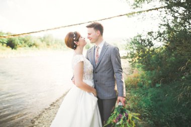 Zarif nazik şık damat ve gelin taşlarla Nehri yakınında. Evlilik çift aşık