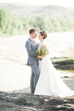 Gelin ve damat güzel düğün buket tutarak. Nehir kenarında poz