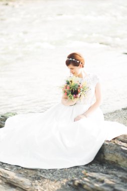 Buket ile nehrin yanında poz ise muhteşem güzel gelin gülümsüyor