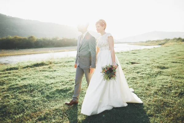 Superbe mariée et marié élégant marchant dans un paysage ensoleillé, couple de mariage, montagnes de cérémonie de luxe avec vue imprenable, espace pour le texte — Photo