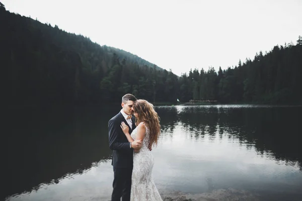 Hermosa pareja de boda besándose y abrazándose cerca de la montaña con vista perfecta —  Fotos de Stock