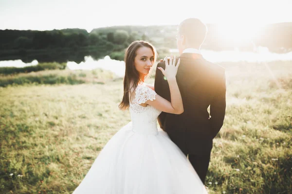 Hermosa pareja romántica de recién casados abrazándose en el parque en la puesta del sol —  Fotos de Stock