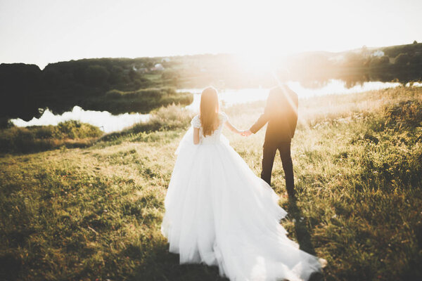 Newly married couple running and jumping in park while holding hands