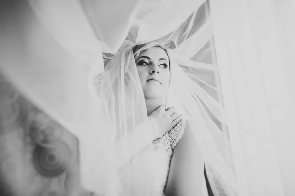 Preciosa novia en bata posando y preparándose para la ceremonia de boda cara en una habitación — Foto de Stock