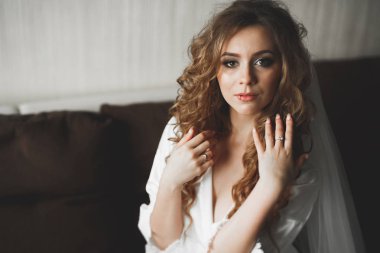 Cüppeli muhteşem gelin bir odada düğün töreni için poz veriyor ve hazırlanıyor.