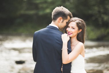 Zarif nazik şık damat ve gelin taşlarla Nehri yakınında. Evlilik çift aşık