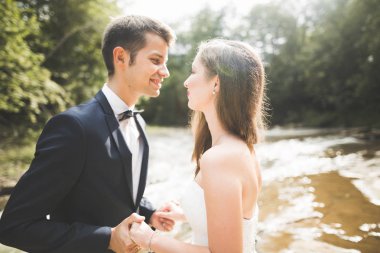 Zarif nazik şık damat ve gelin taşlarla Nehri yakınında. Evlilik çift aşık