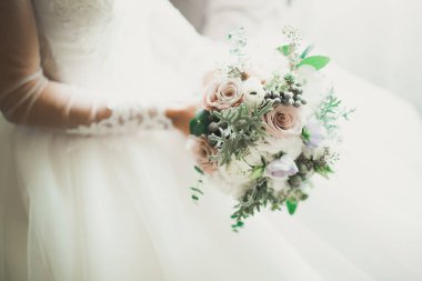 Gelin çiçekli büyük ve güzel bir düğün buketi tutuyor.