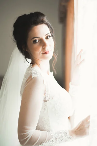 Красива наречена в модній весільній сукні з пір'ям з розкішним захоплюючим макіяжем і зачіскою, студія в приміщенні фотосесії — стокове фото