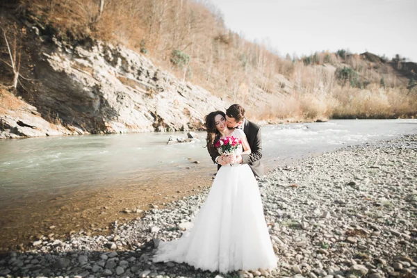 Élégant élégant mariée brune heureuse et marié magnifique sur le fond d'une belle rivière dans les montagnes — Photo