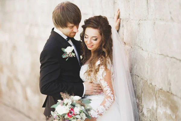 Stilvolles Brautpaar spaziert am Hochzeitstag mit Blumenstrauß durch den Park — Stockfoto