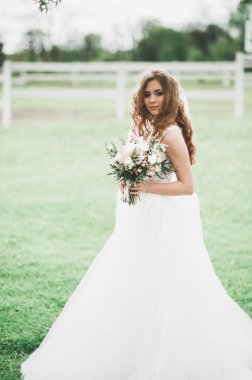 Gelinlik içinde dışarıda poz veren güzel gelin.