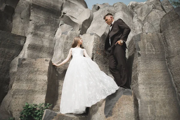 Para ślub pozowanie na wielkie kamienie. Panna młoda i pan młody — Zdjęcie stockowe