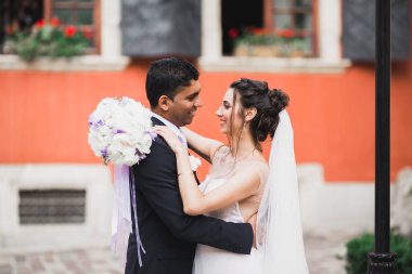 Doğadaki düğün çifti birbirine sarılıyor. Beyaz elbiseli güzel bir kız. Takım elbiseli adam