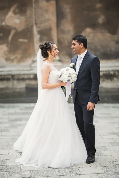 Muhteşem mutlu çift birbirine yakın duruyor ve eski şehir geçmişine, düğün fotoğrafına, Avrupa şehrine, Lviv 'de düğün gününe bakıyor. — Stok fotoğraf