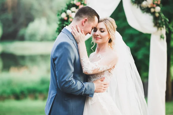 Schöne Braut und Bräutigam umarmen und küssen sich am Hochzeitstag im Freien — Stockfoto