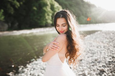 Nehrin kenarında duran uzun saçlı güzel gelinin portresi.