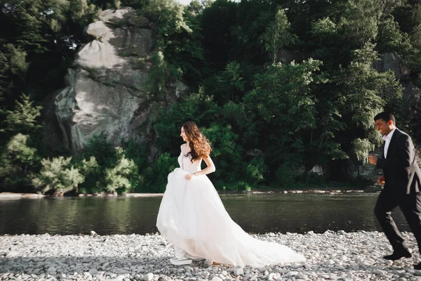 Svatební pár, ženich a nevěsta běží, venku u řeky — Stock fotografie