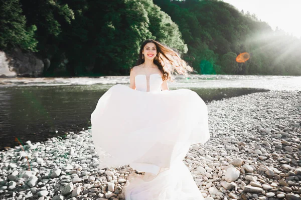 Retrato de la novia impresionante con el pelo largo de pie junto al río —  Fotos de Stock