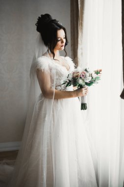 Çekici gelinin portresi, uzun saçlı, büyük buketli poz veren.