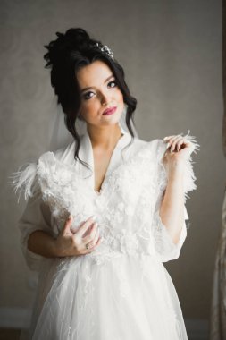 Cüppeli muhteşem gelin bir odada düğün töreni için poz veriyor ve hazırlanıyor.