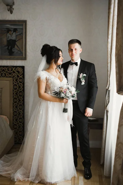 Hermosa joven pareja de boda posando con ramo de flores en las manos —  Fotos de Stock