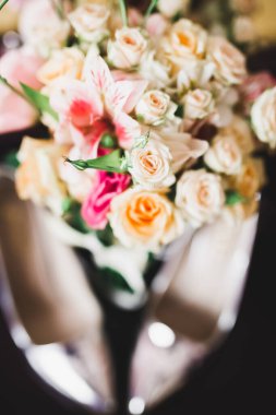 Bir çift zarif ve şık gelin ayakkabısı ile bir buket gül ve diğer çiçeklerle.