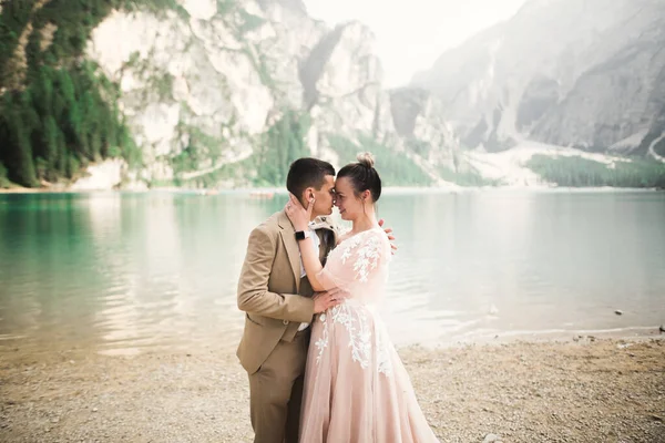 Hermosa pareja feliz de pie cerca el uno del otro y mirando a los ojos cerca de un hermoso lago en las montañas — Foto de Stock
