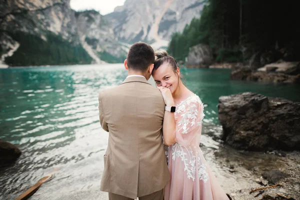 ロマンチックな結婚式の瞬間、新婚夫婦は山の中の美しい湖の近くに抱きつく肖像画、花嫁と新郎を笑っています — ストック写真