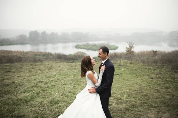 Romántico, cuento de hadas, feliz pareja recién casada abrazándose y besándose en un parque, árboles en el fondo — Foto de Stock