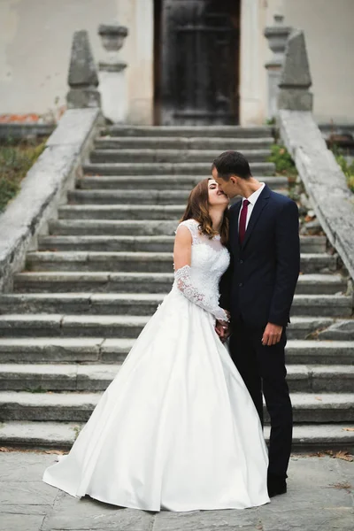 Gyönyörű menyasszony és vőlegény ölelkeznek és csókolóznak az esküvő napján. — Stock Fotó