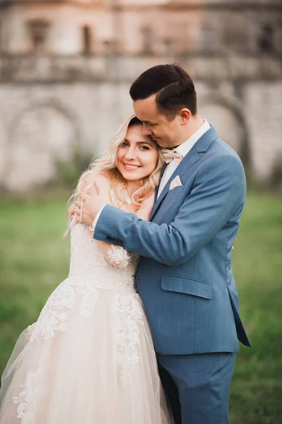 Beautiful bride and groom embracing and kissing on their wedding day outdoors — Stock Photo, Image