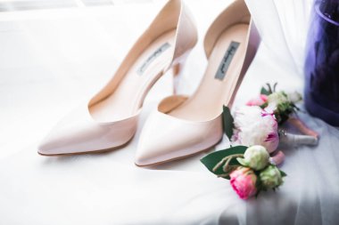 Bir çift zarif ve şık gelin ayakkabısı ile bir buket gül ve diğer çiçeklerle