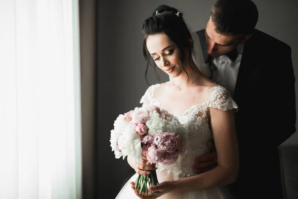 La pareja de boda en la naturaleza se está abrazando. Hermosa modelo chica en vestido blanco. Hombre de traje — Foto de Stock