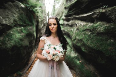 Gelin çiçekli büyük ve güzel bir düğün buketi tutuyor.