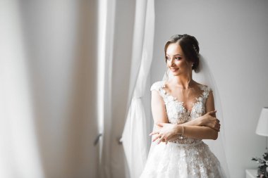 Beyaz elbiseli lüks gelin düğün törenine hazırlanırken poz veriyor.