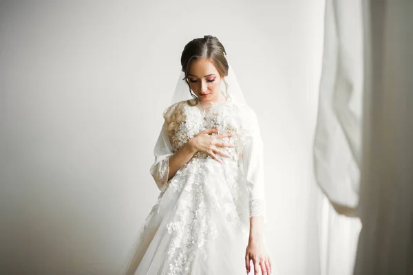 Prachtige bruid in badjas poseren en voor te bereiden op de bruiloft ceremonie gezicht in een kamer — Stockfoto