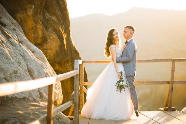 Doğadaki düğün çifti birbirine sarılıyor. Beyaz elbiseli güzel bir kız. Takım elbiseli adam