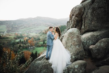 Dağların arka planında sevgi dolu bir koca ve kadın. Sevgili çift duygusal olarak vakit geçirir.